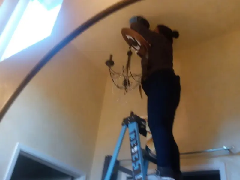 Electrician installing a chandelier in a Jay residence